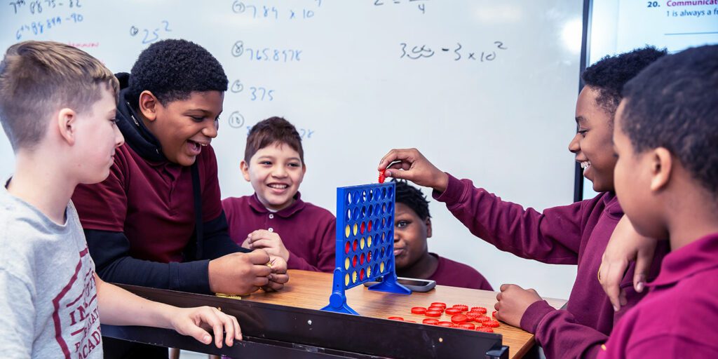 In the classroom, a group of happy students plays connect all four game.